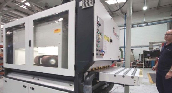 A Wrightform shopfloor worker stands next to one of their machines.