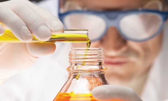 man in white coat pouring orange liquid with into a glass