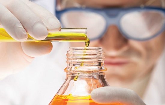 man in white coat pouring orange liquid with into a glass
