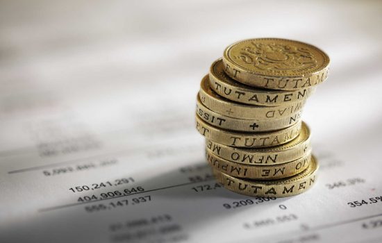 Stack of pound coins on financial figures - image courtesy of Depositphotos.